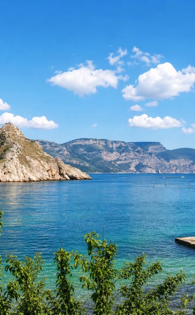 Turquoise bay framed by rocky headlands and a hilltop fortress ruin on the Crimean coast near Sevastopol.