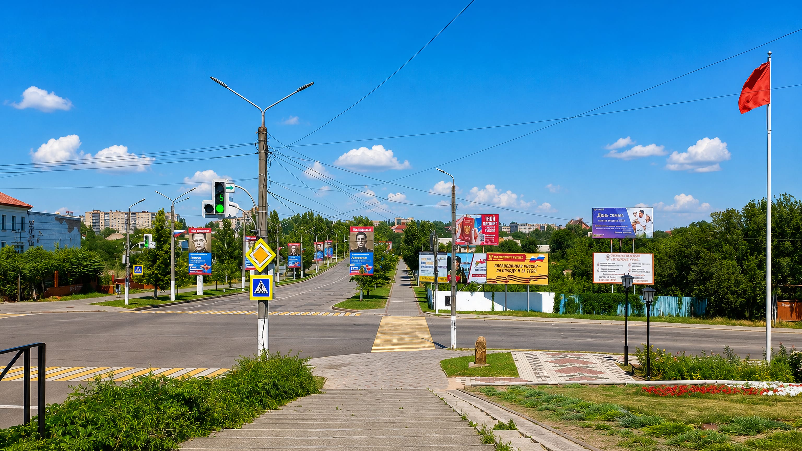 Wide boulevard in Melitopol, Ukraine, lined with billboards and street lamps under a clear blue sky.