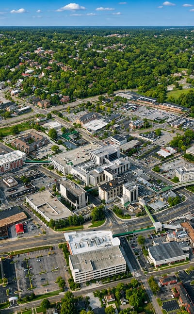 Aerial view of Huntsville, Alabama, with low-rise downtown buildings among green tree-lined streets.