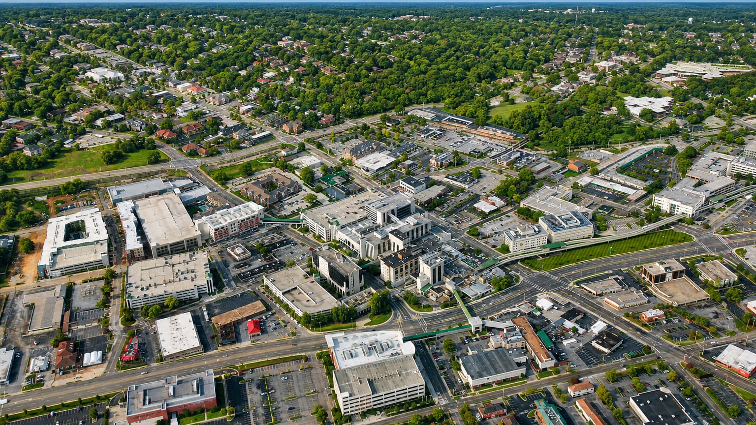 Aerial view of Huntsville, Alabama, with low-rise downtown buildings among green tree-lined streets.