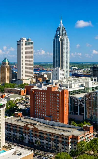 Downtown Mobile, Alabama, skyline led by the spired RSA Battle House Tower, with the port and bay beyond.