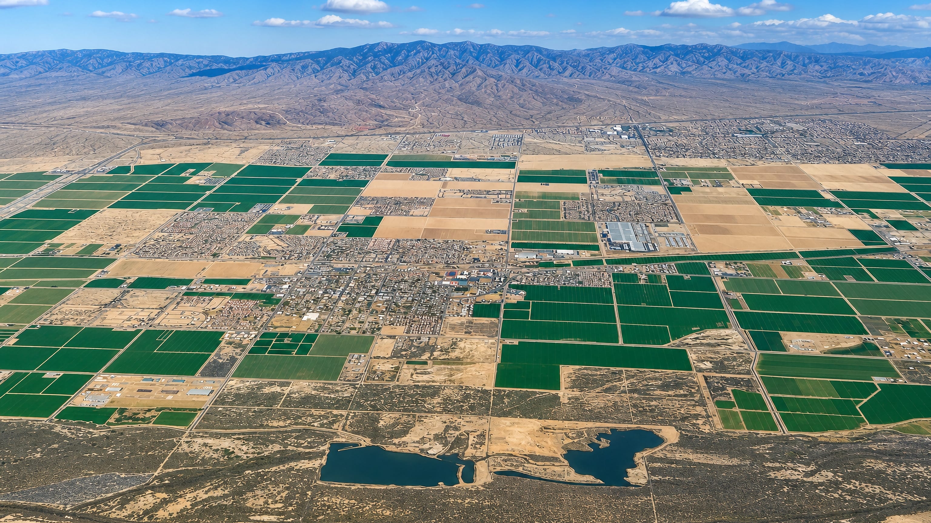 High aerial view of Buckeye, Arizona, its irrigated field grid and desert ringed by mountains
