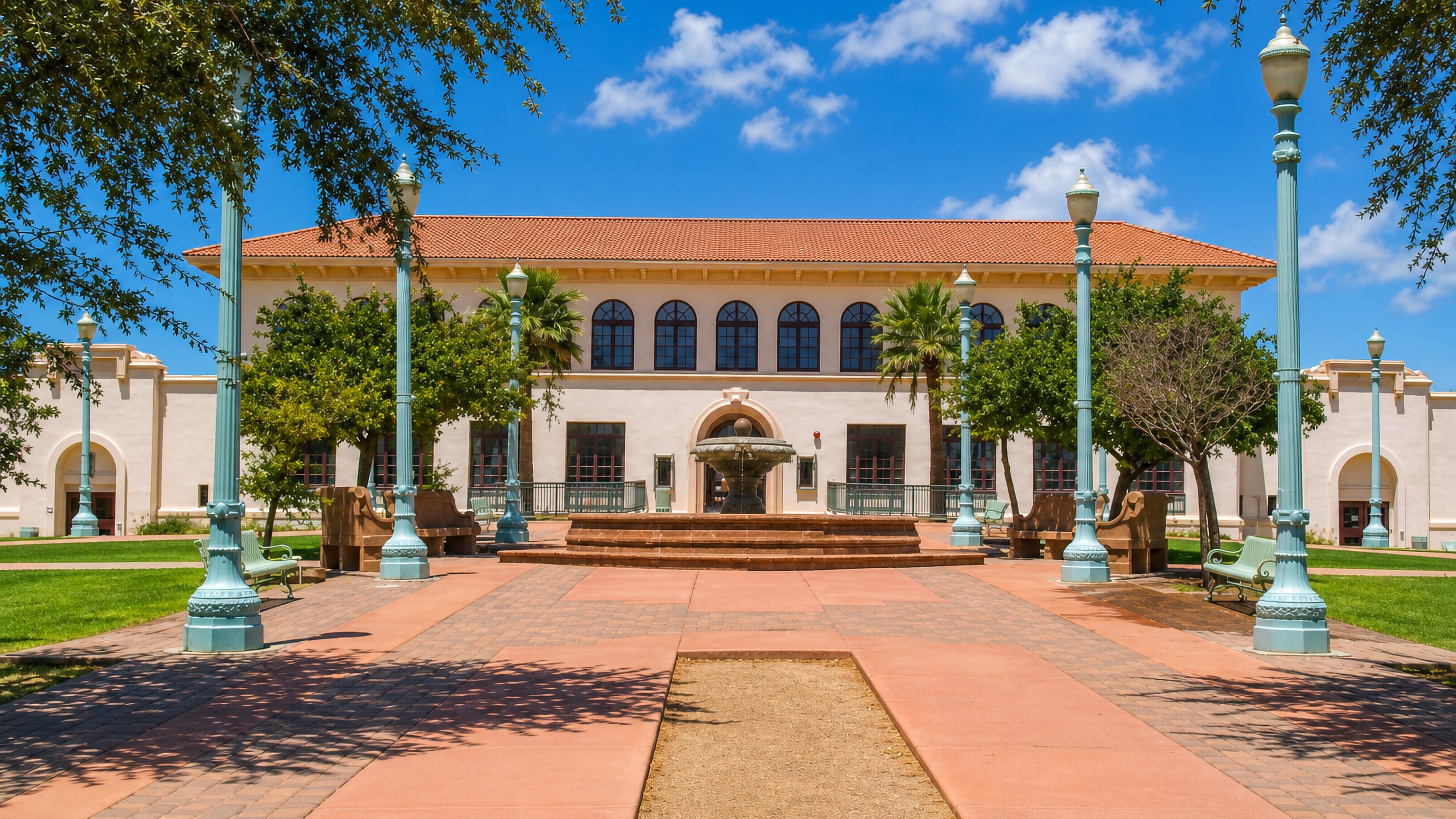 Mission-revival civic building with tiled roof, fountain and palms on a plaza in Casa Grande, Arizona