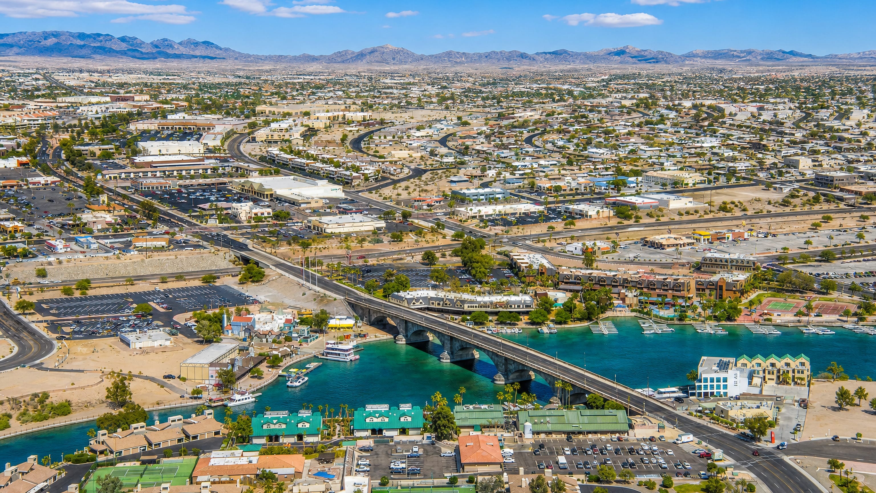 London Bridge crossing the turquoise Bridgewater Channel past marinas and desert hills, Lake Havasu City, Arizona.
