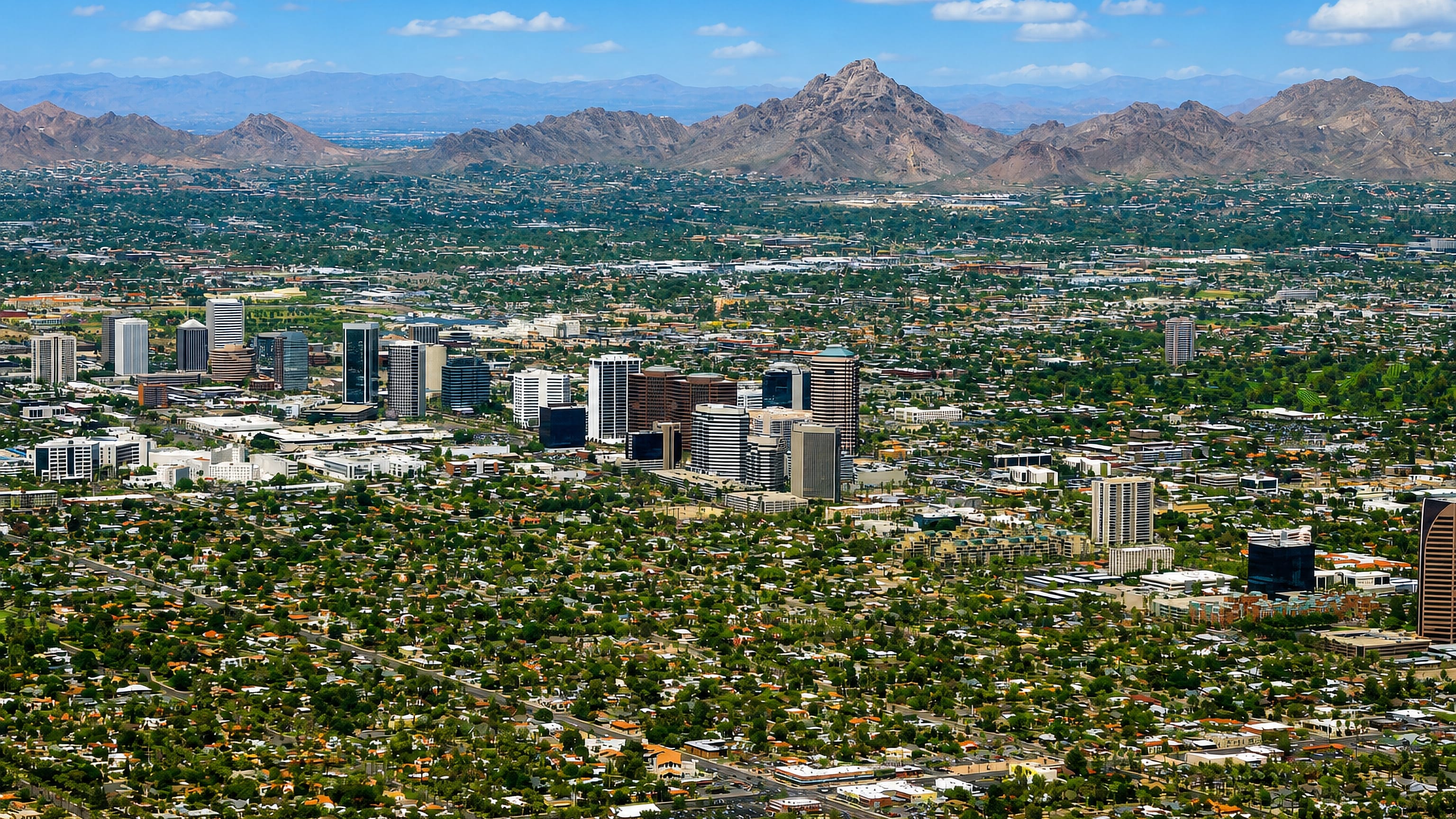 Midtown Phoenix high-rises in the Encanto district with leafy streets and Piestewa Peak on the horizon