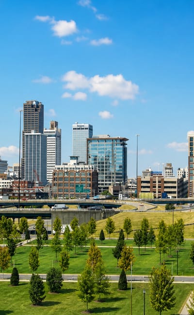 Little Rock, Arkansas, downtown skyline rising beyond a landscaped park and highway.