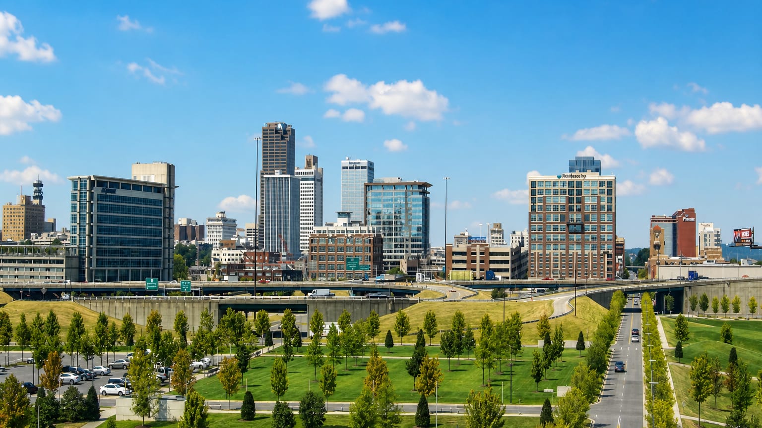 Little Rock, Arkansas, downtown skyline rising beyond a landscaped park and highway.