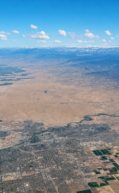 Aerial view of Bakersfield amid San Joaquin Valley farmland below distant mountains, California.