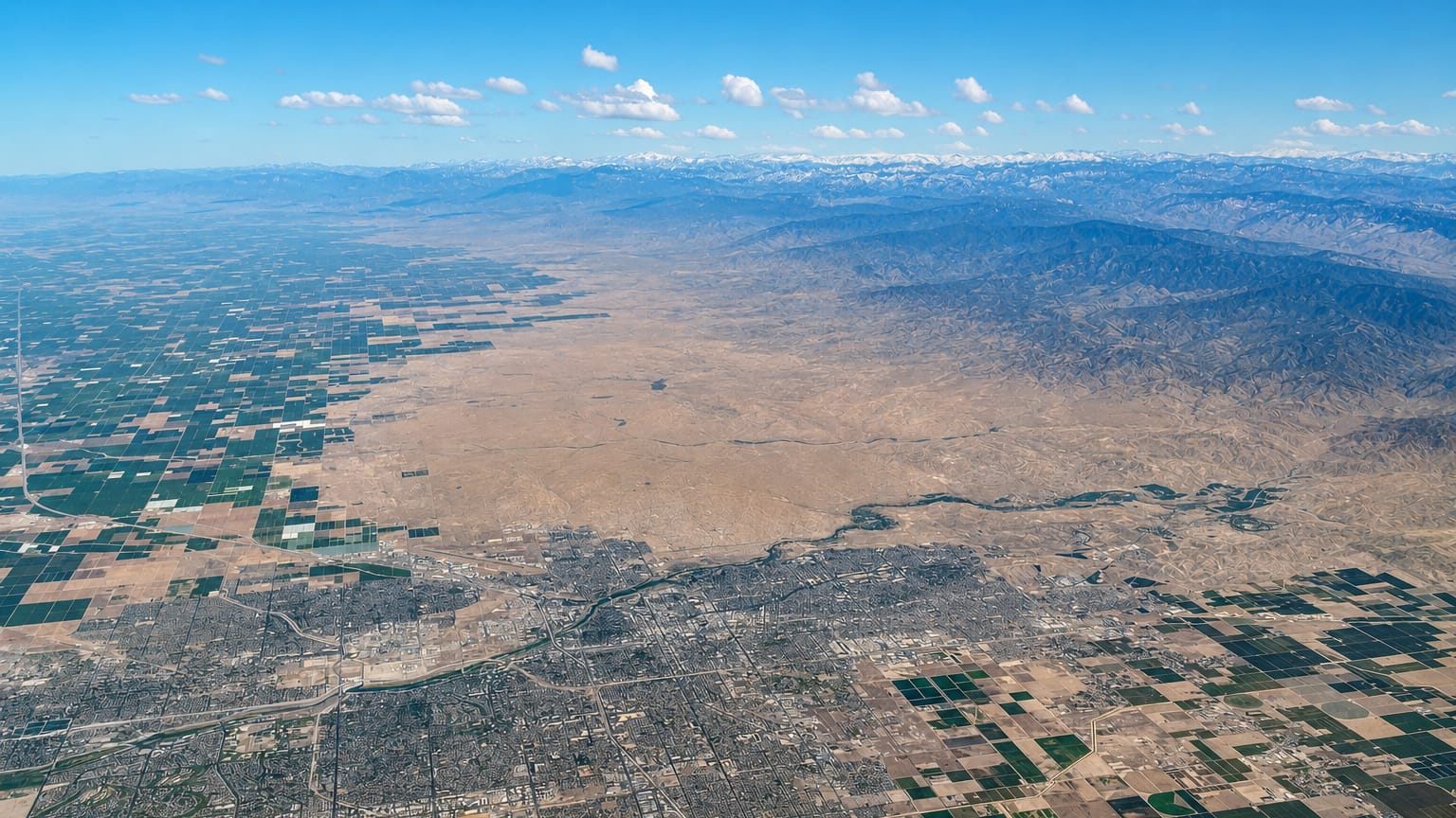 Aerial view of Bakersfield amid San Joaquin Valley farmland below distant mountains, California.