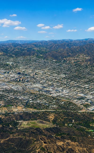 Aerial view of Burbank, California in the valley below wooded hills and mountains