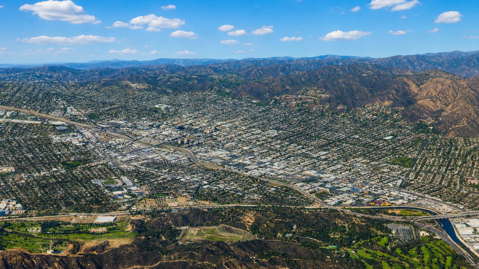 Aerial view of Burbank, California in the valley below wooded hills and mountains