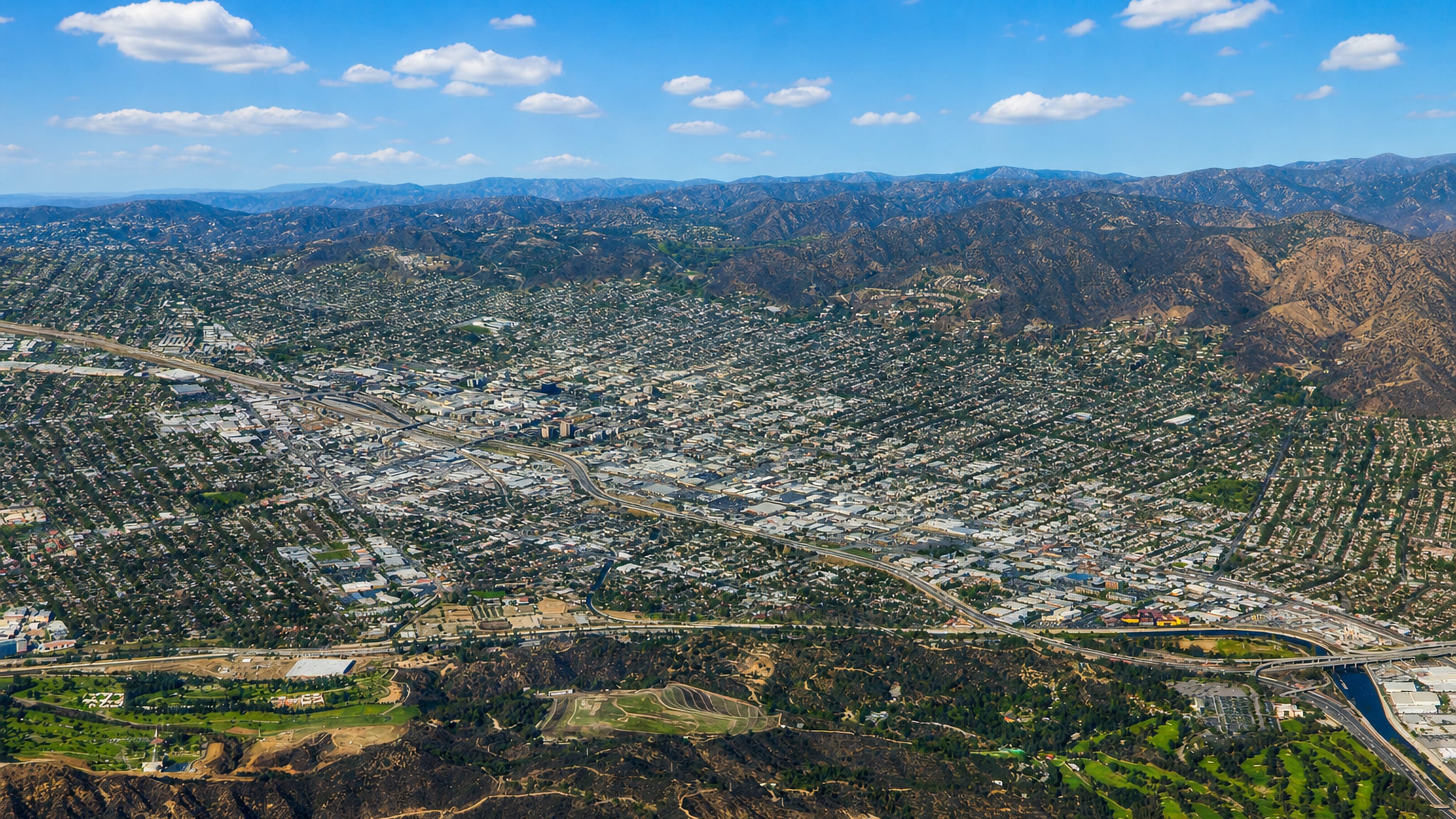 Aerial view of Burbank, California in the valley below wooded hills and mountains