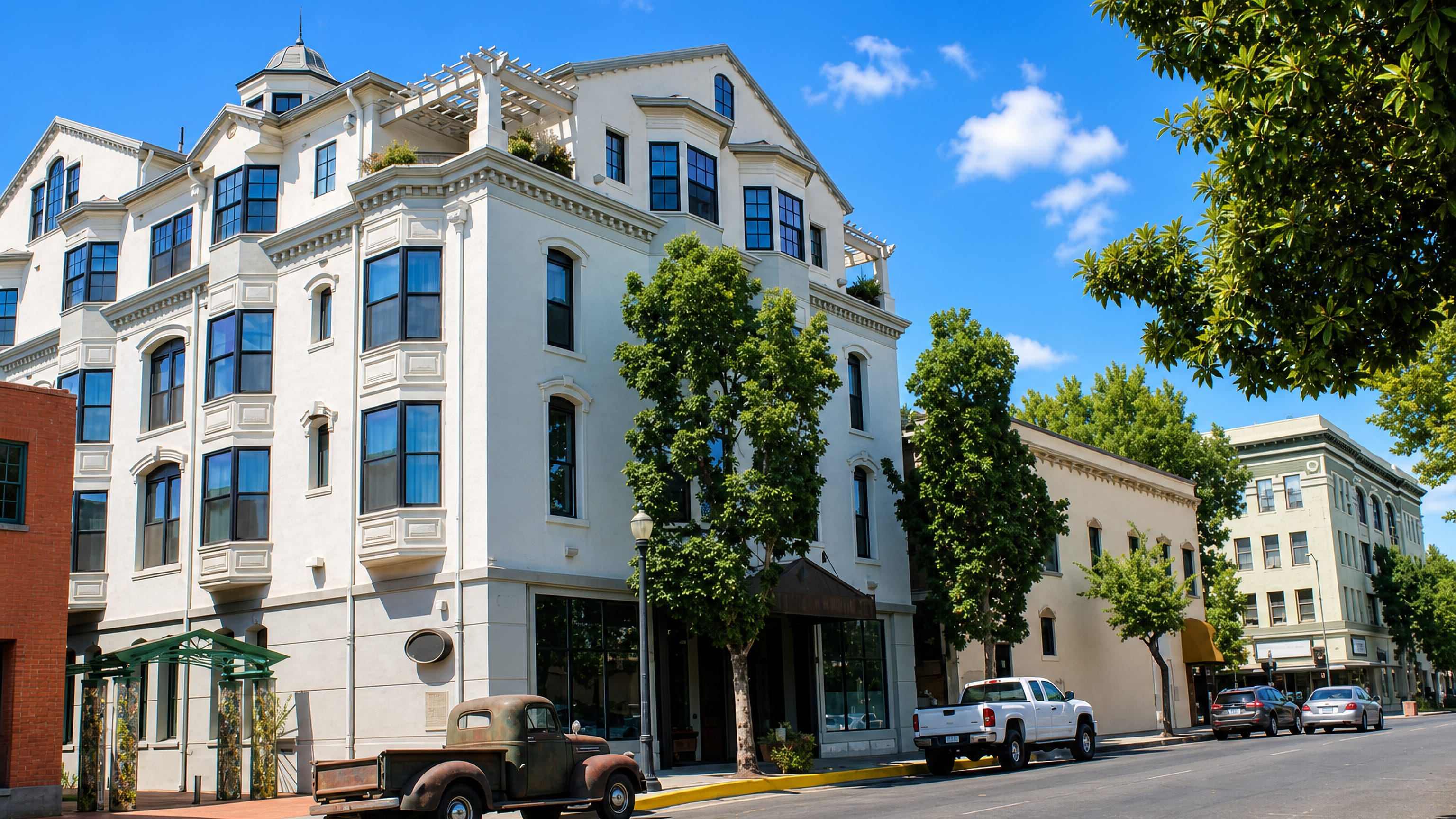 Historic downtown Chico, California, with a white Victorian corner building, shade trees and a vintage pickup.