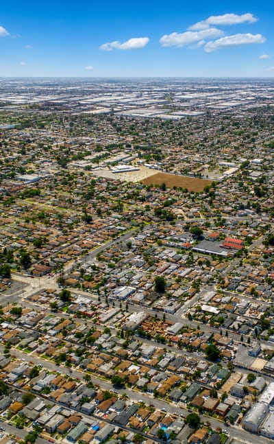 Aerial view over Compton, California, a flat grid of homes stretching to distant warehouse districts