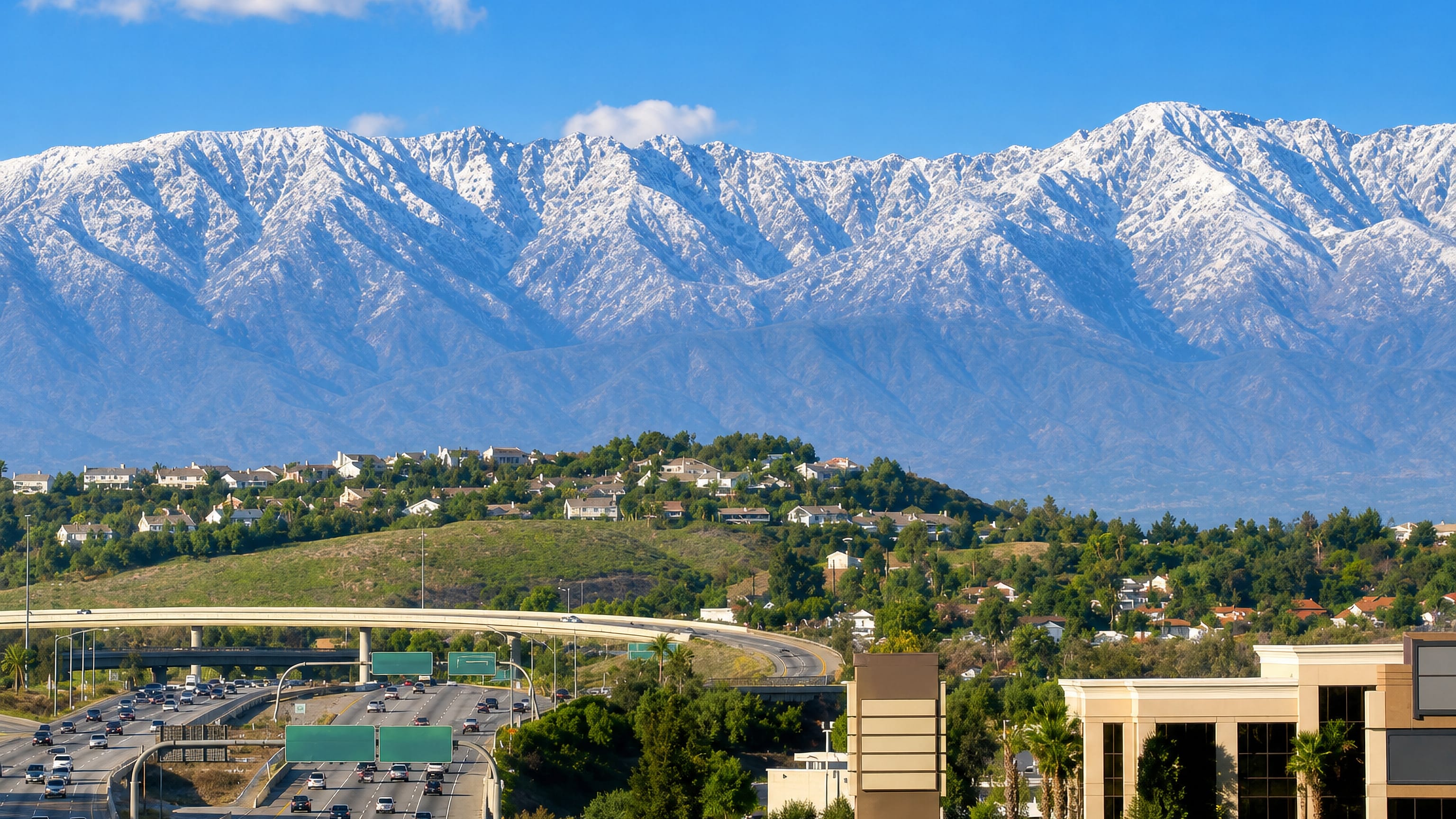 Traffic on the freeway through Corona, California, below the snow-capped ridges of the Inland Empire.