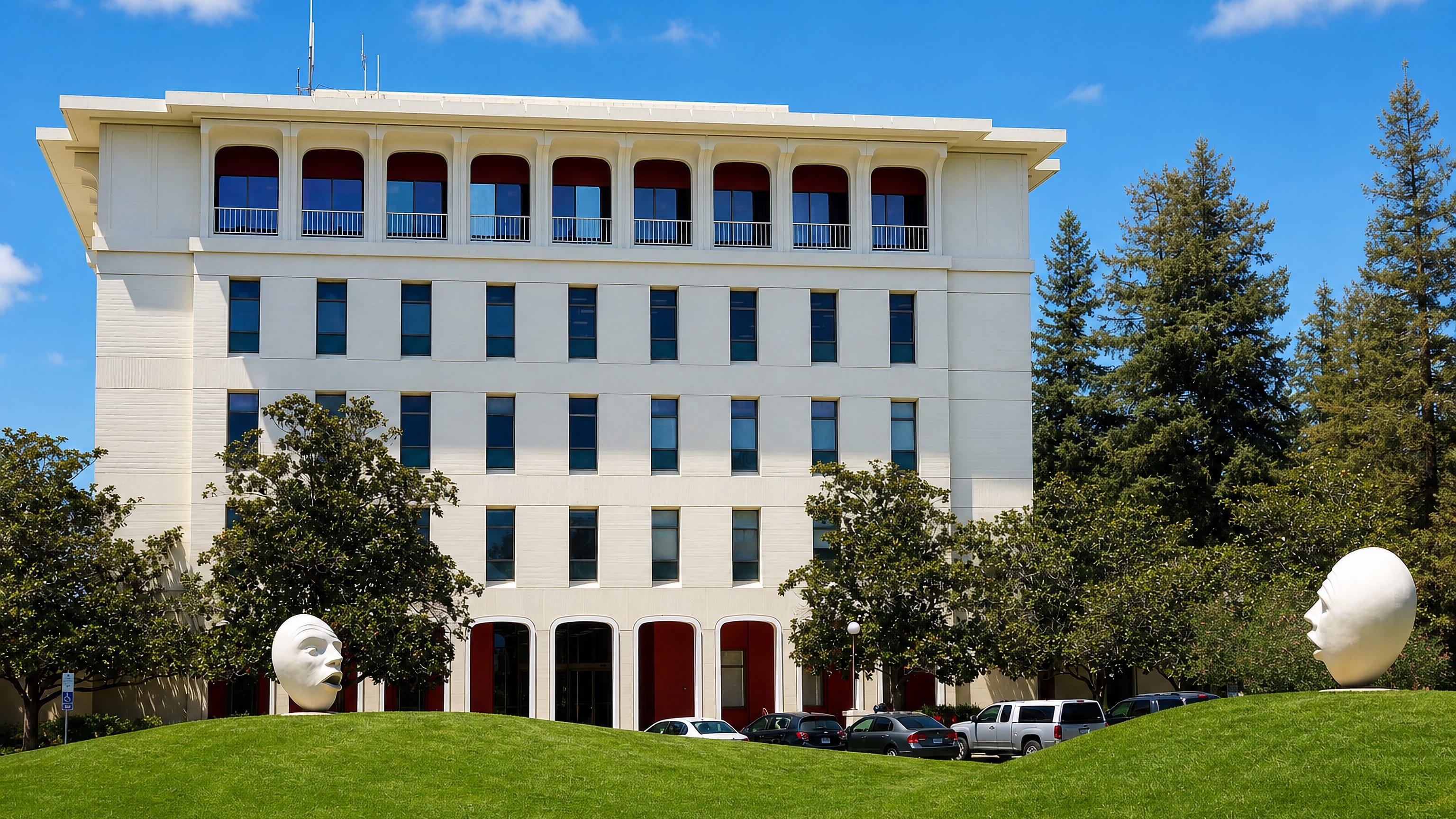 Mrak Hall at UC Davis, flanked by the campus Egghead sculptures on a green lawn under a clear blue sky.