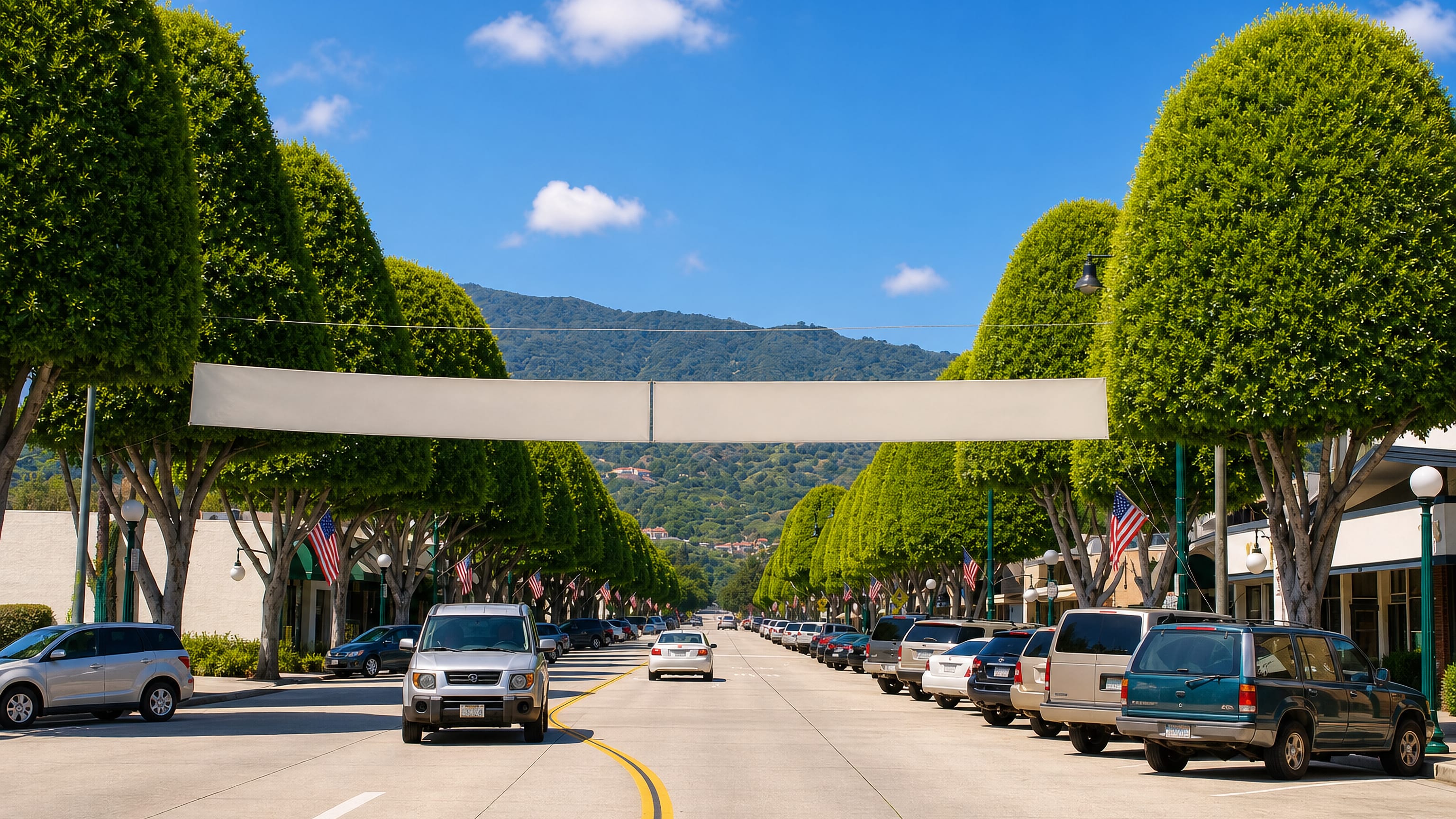 Flag-lined, tree-canopied main street in Glendora, California, running toward the San Gabriel foothills