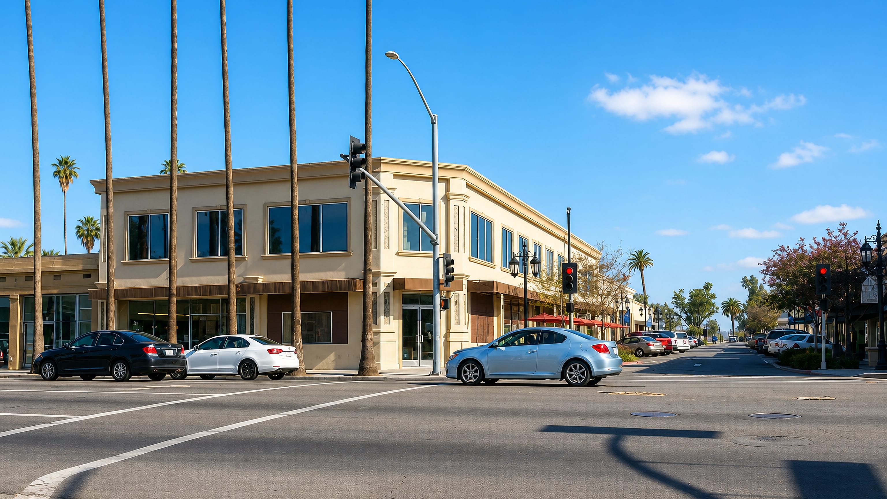 Palm-lined street corner in Hemet, California, with a two-storey stucco commercial building and passing cars.