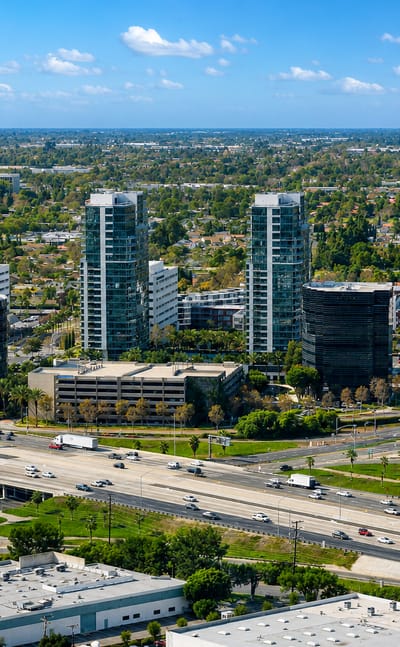Aerial view of Irvine, California high-rise residential towers and office parks beside a busy freeway