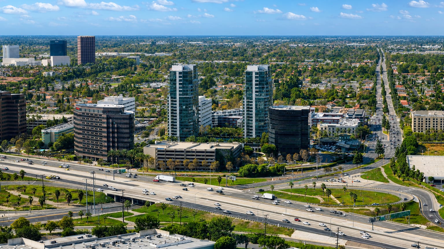 Aerial view of Irvine, California high-rise residential towers and office parks beside a busy freeway