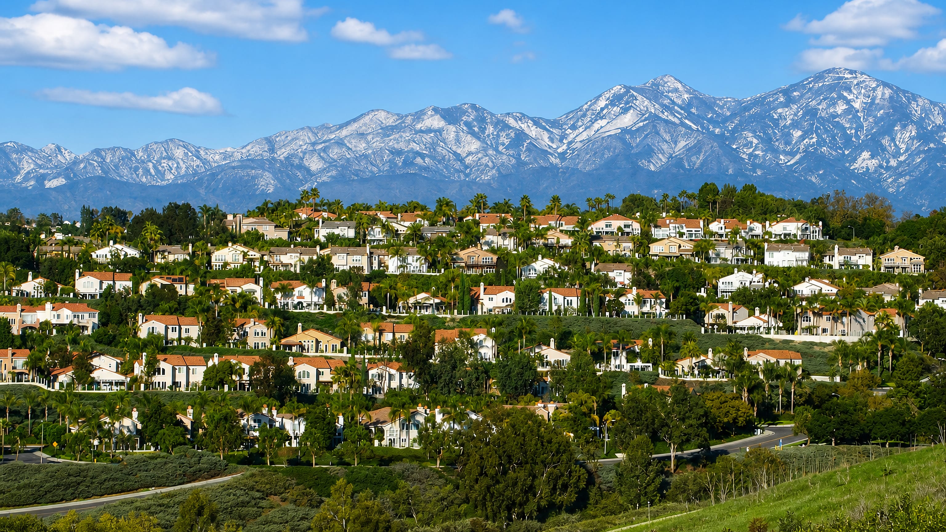Tile-roofed hillside homes and palms in Laguna Niguel, California, with snow-dusted mountains beyond