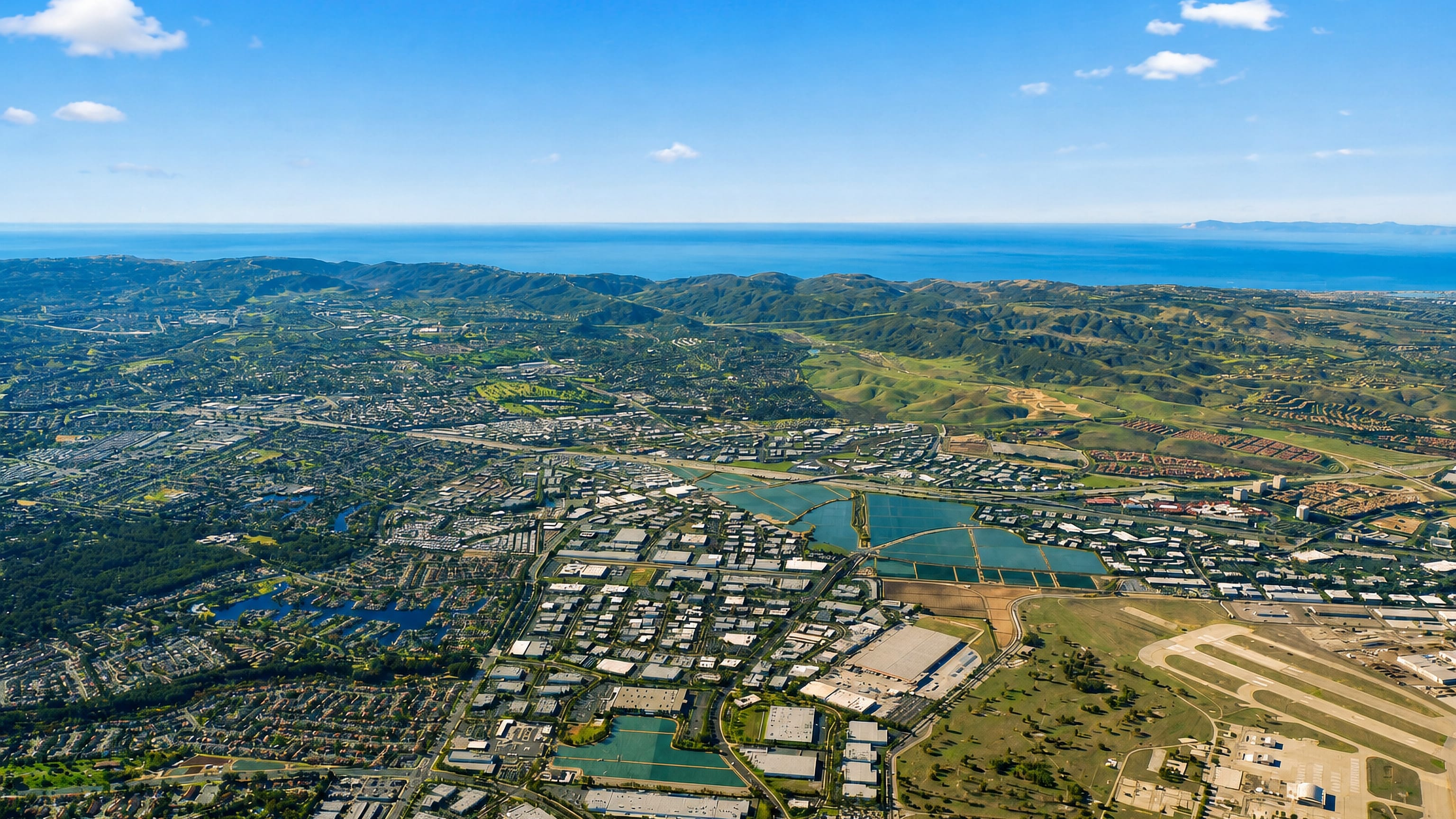 Aerial view over Lake Forest, California, with business parks, lakes, rolling hills and the Pacific beyond