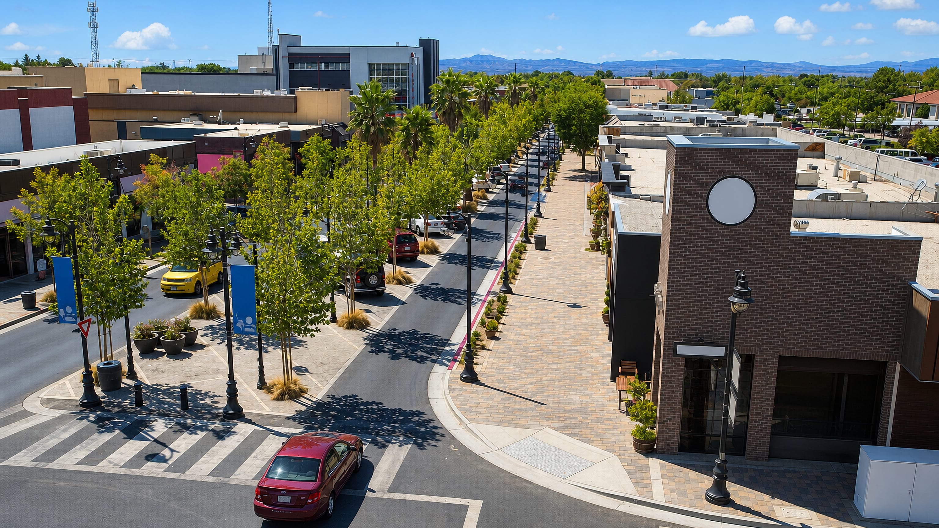 Palm-lined rambla and low-rise storefronts along The BLVD in downtown Lancaster, California, with desert mountains beyond
