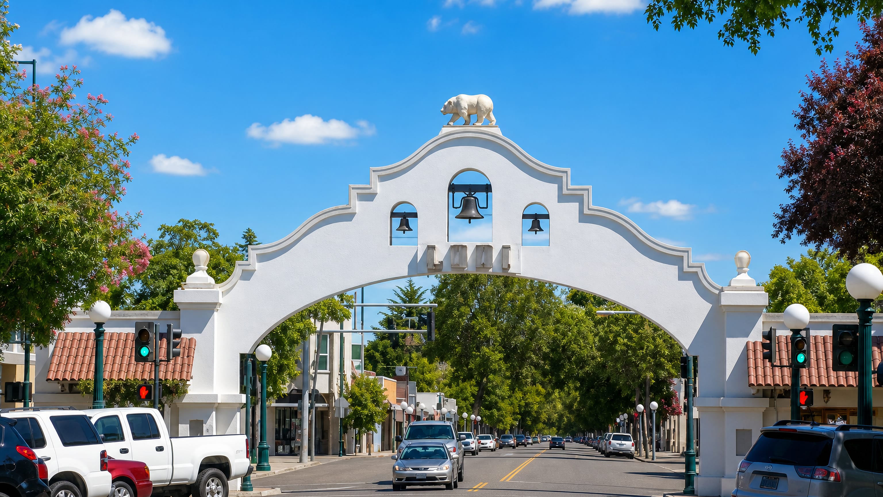 The white Mission-style Lodi Arch with its bells and bear statue spanning downtown Pine Street in Lodi, California.