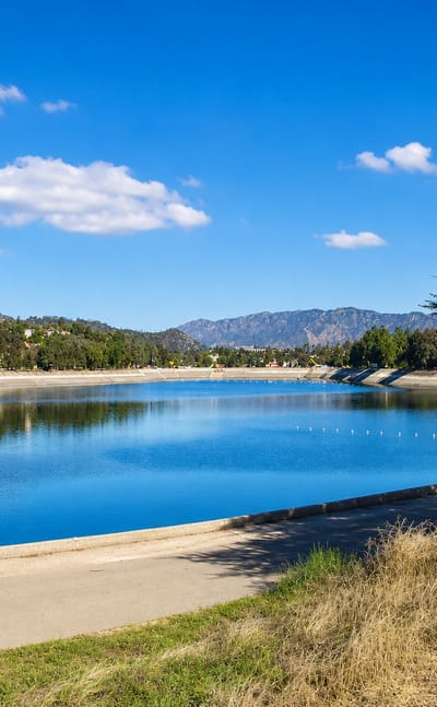 Silver Lake Reservoir with its concrete embankment, hillside homes and the San Gabriel Mountains beyond