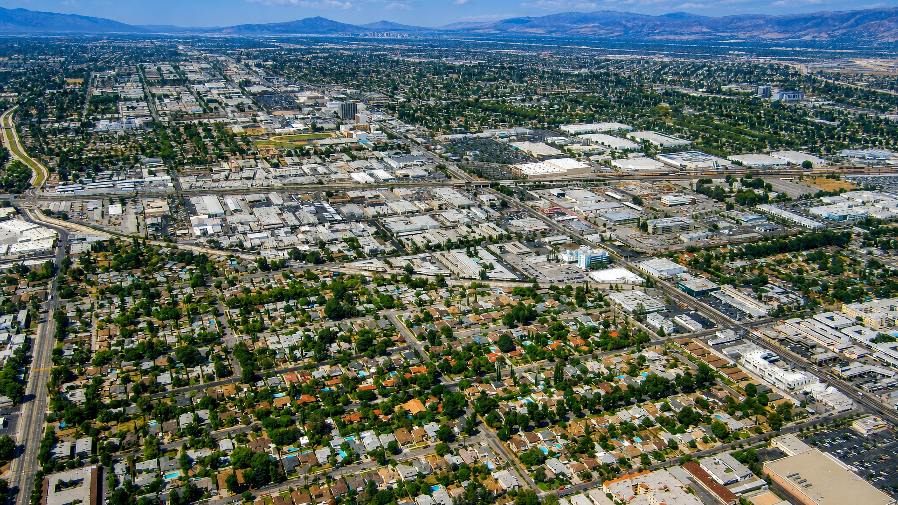 Aerial over Van Nuys, Los Angeles: the flat San Fernando Valley street grid ringed by distant mountains.