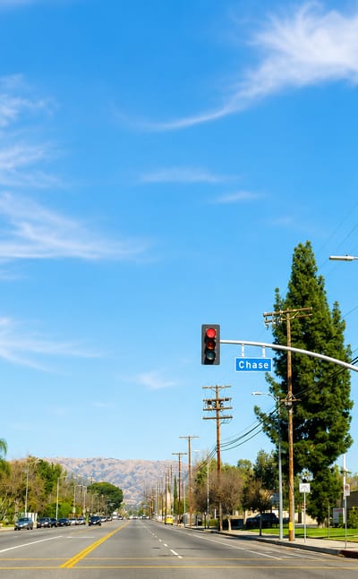 Wide suburban boulevard with palm trees at Chase Street in Winnetka, with mountains in the distance