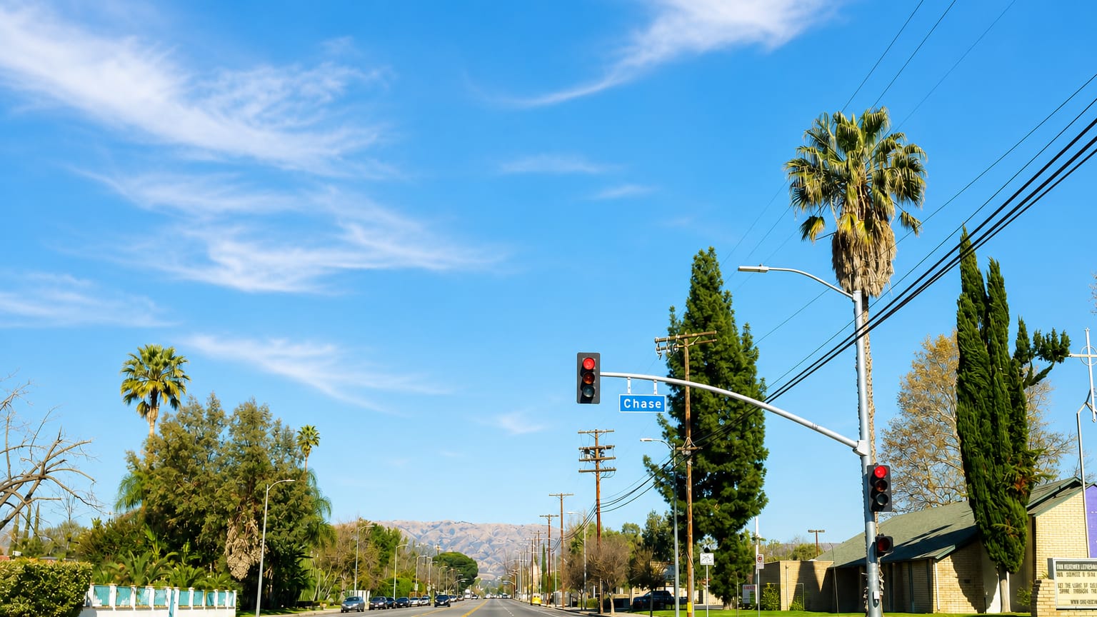 Wide suburban boulevard with palm trees at Chase Street in Winnetka, with mountains in the distance