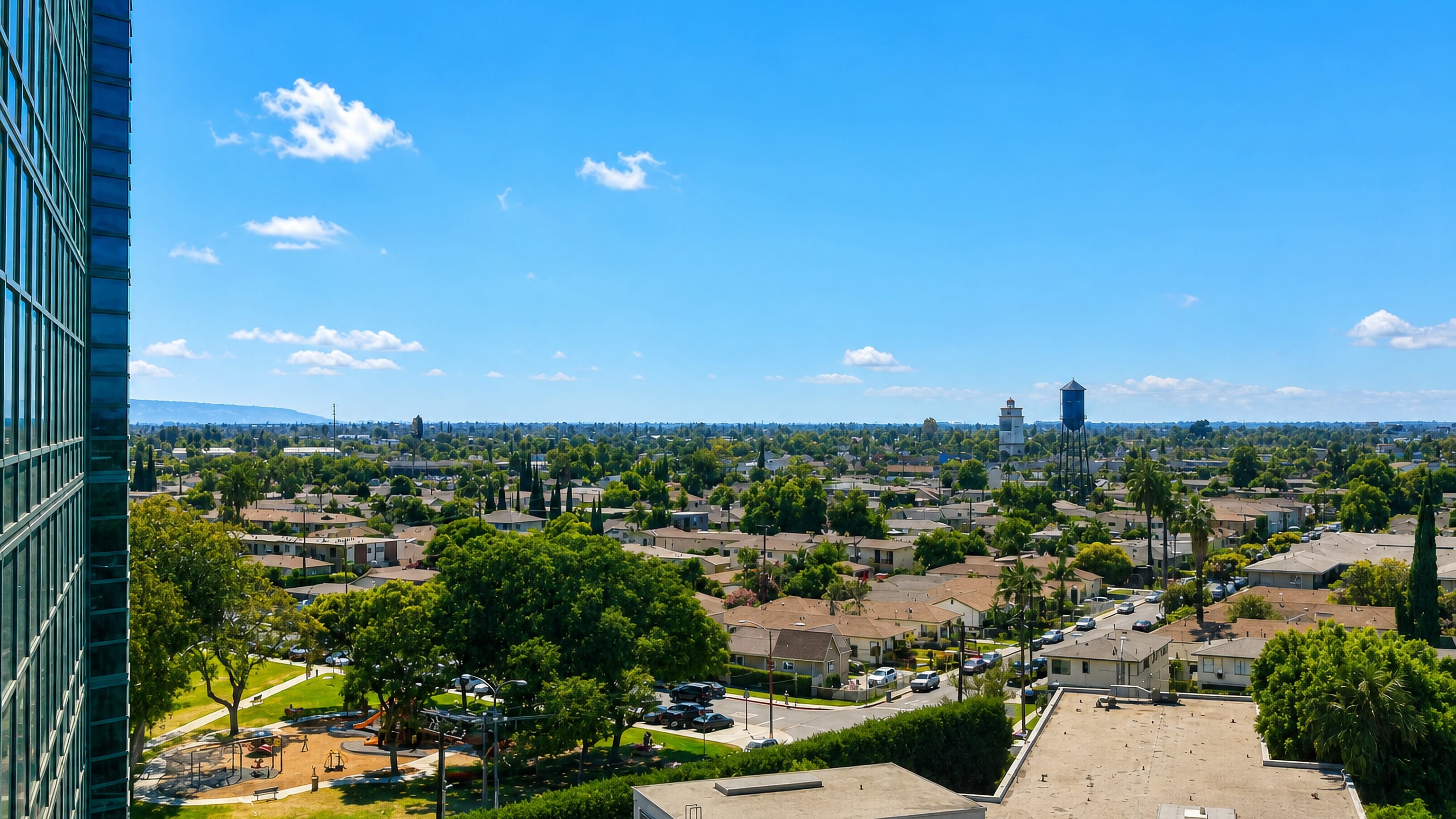 Elevated view over low-rise houses, palms and water towers spread across Lynwood, California.