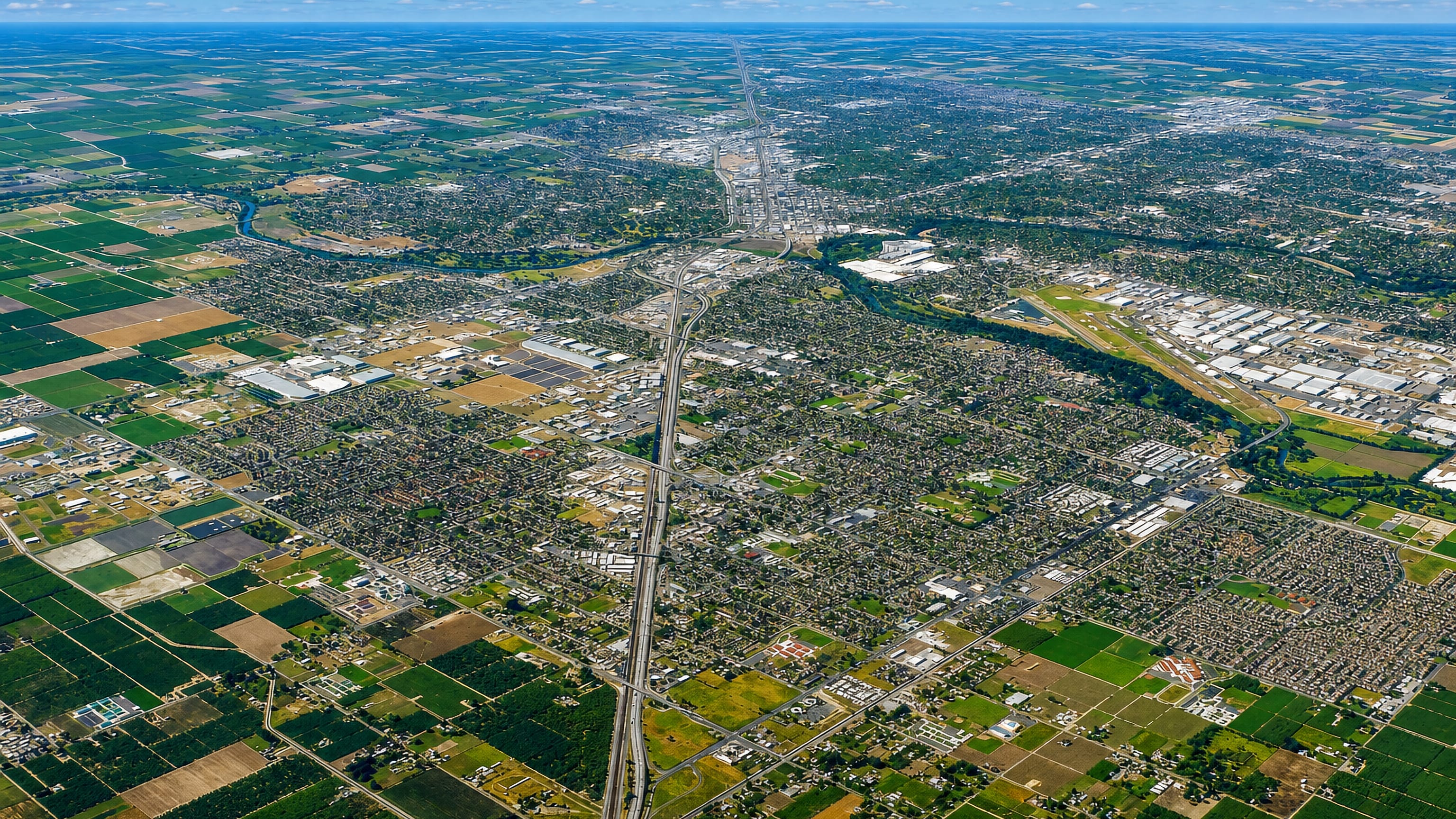 Aerial view of Modesto, California, spreading across Central Valley farmland with a freeway corridor cutting through