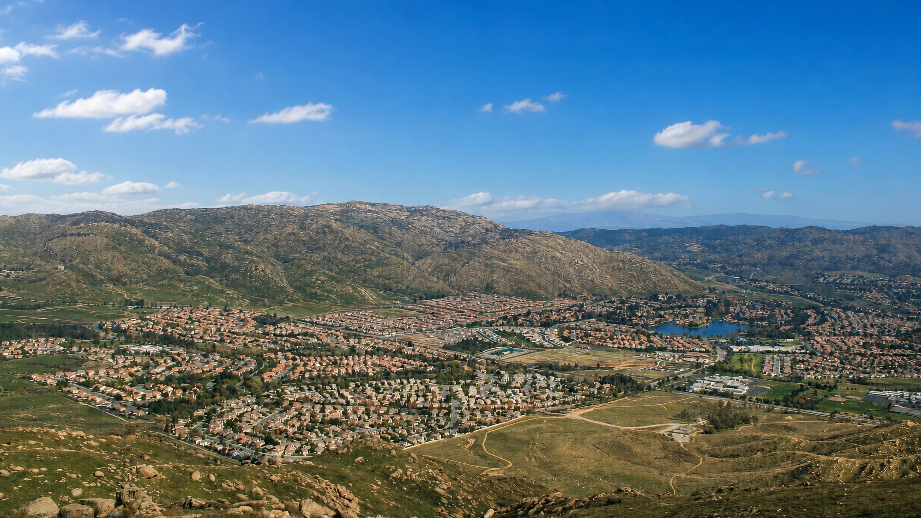 Hilltop view over the suburban sprawl of Moreno Valley, California, beneath dry chaparral hills.