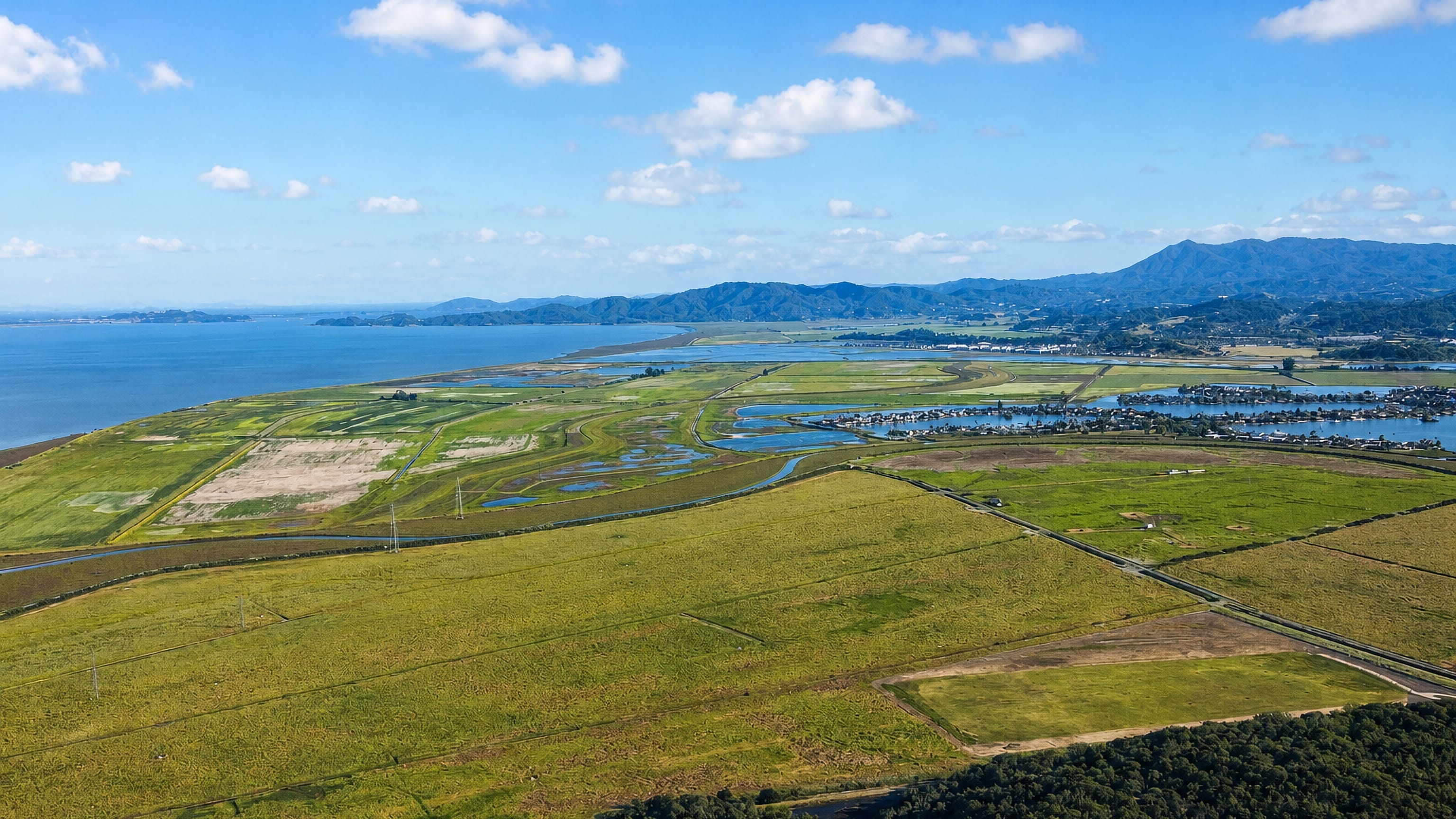 Aerial over the baylands north of Novato, California, with waterside homes and Marin hills beyond.