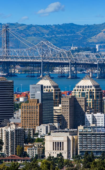 Downtown Oakland skyline with the Tribune Tower and the Bay Bridge cantilever and hills behind