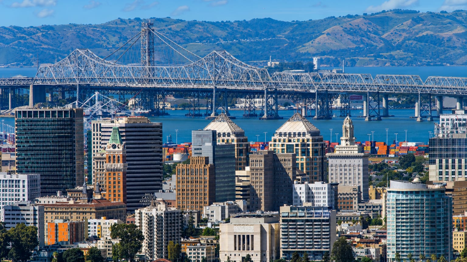 Downtown Oakland skyline with the Tribune Tower and the Bay Bridge cantilever and hills behind