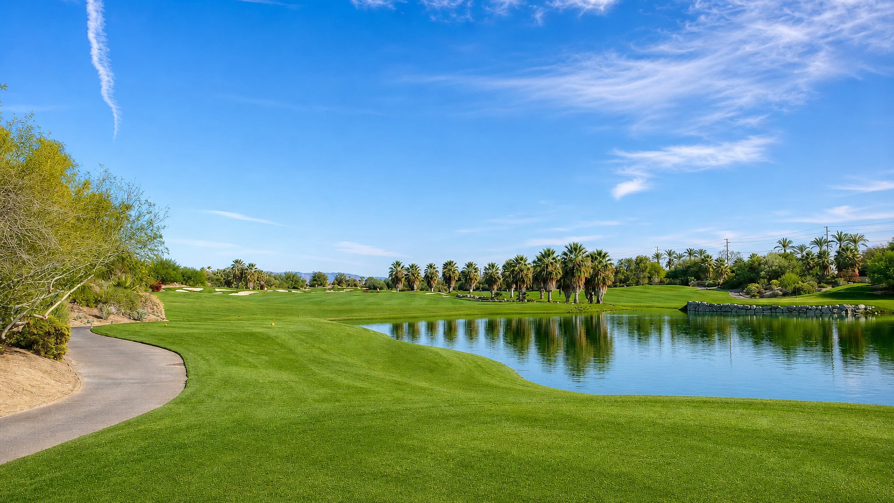 Manicured golf fairway, water hazard and palm trees under a blue sky in Palm Desert, California.