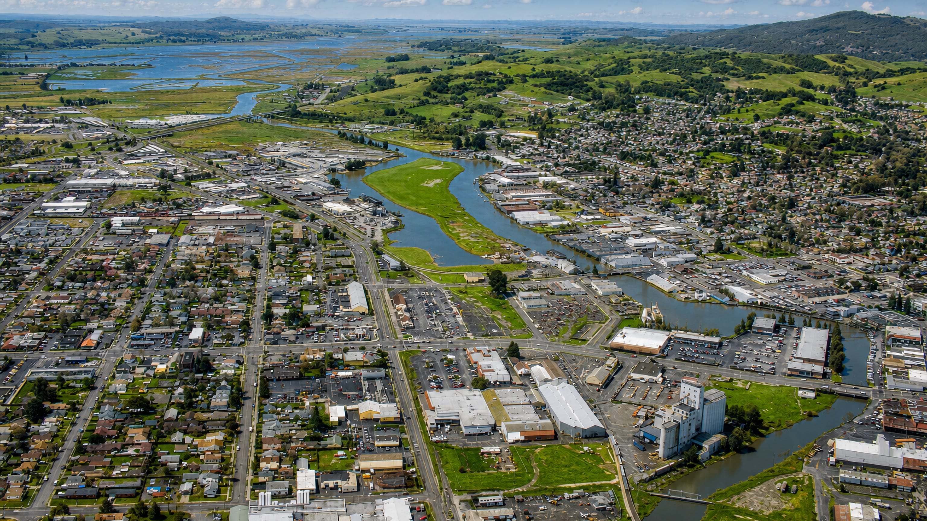 Aerial view of Petaluma, California, its river winding past feed-mill silos toward tidal marshes