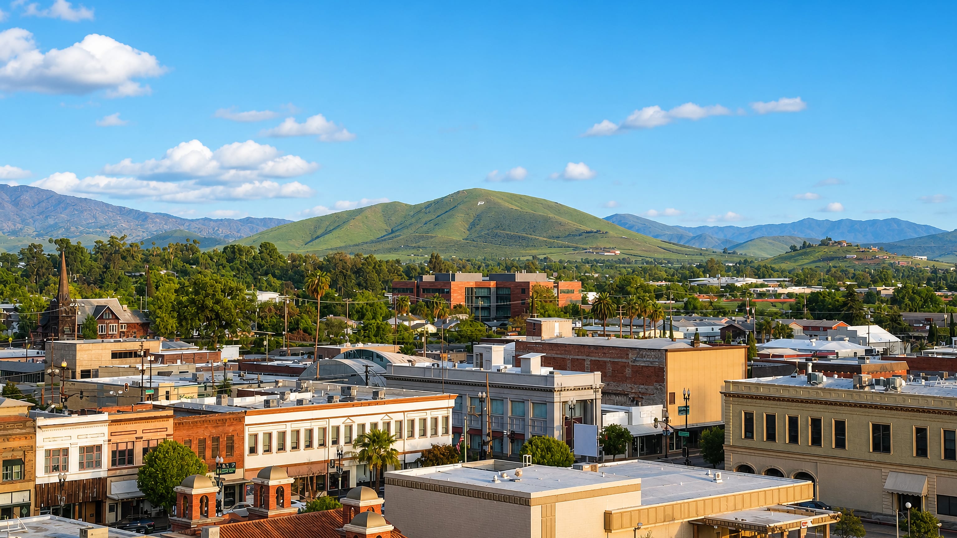 Downtown Porterville, California, its historic brick storefronts backed by the green Sierra foothills.