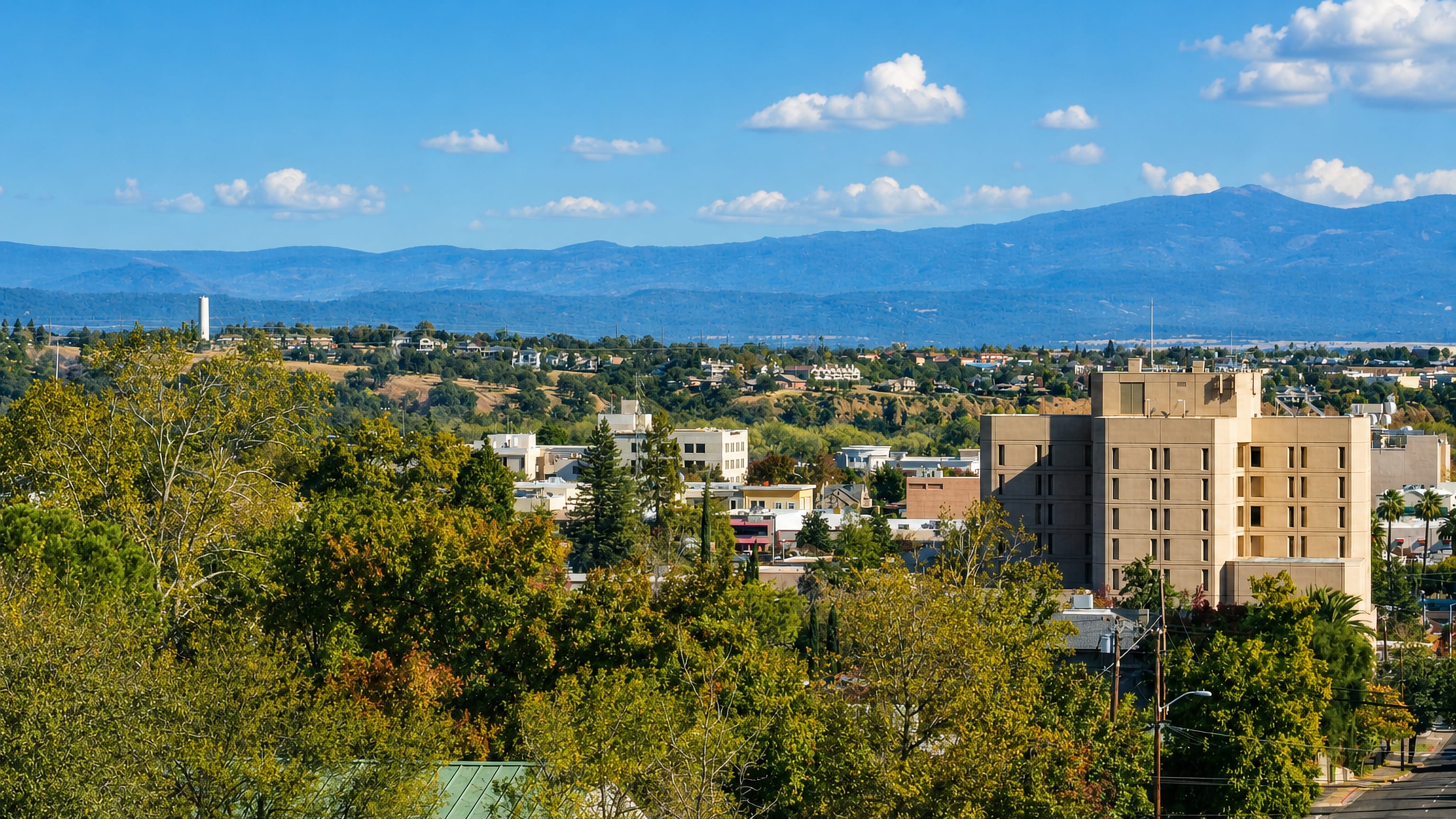 Downtown Redding, California framed by oak canopy with the blue Coast Range foothills rising beyond