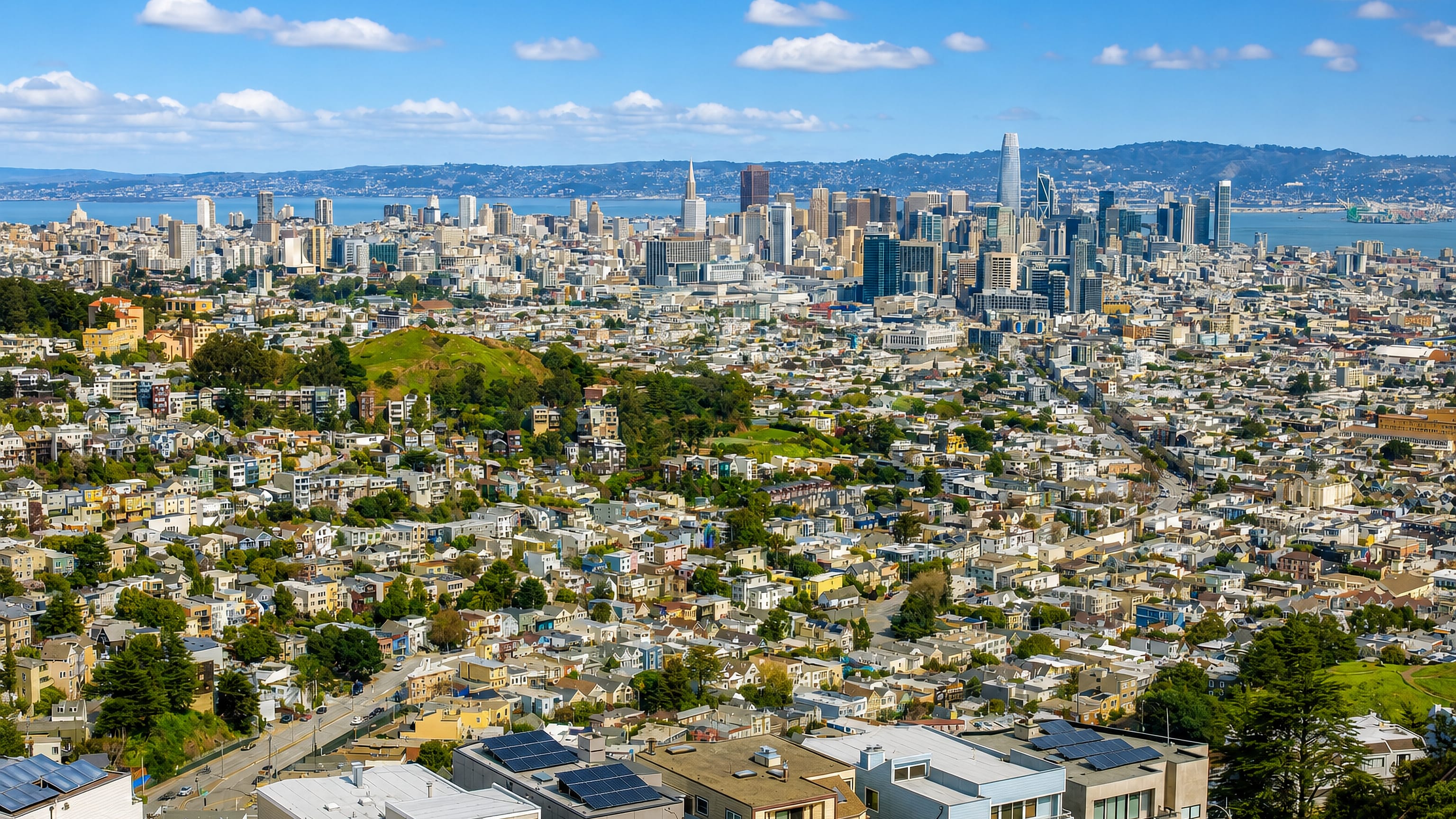 Hillside rooftops of San Francisco's Castro district with the downtown skyline and bay beyond.
