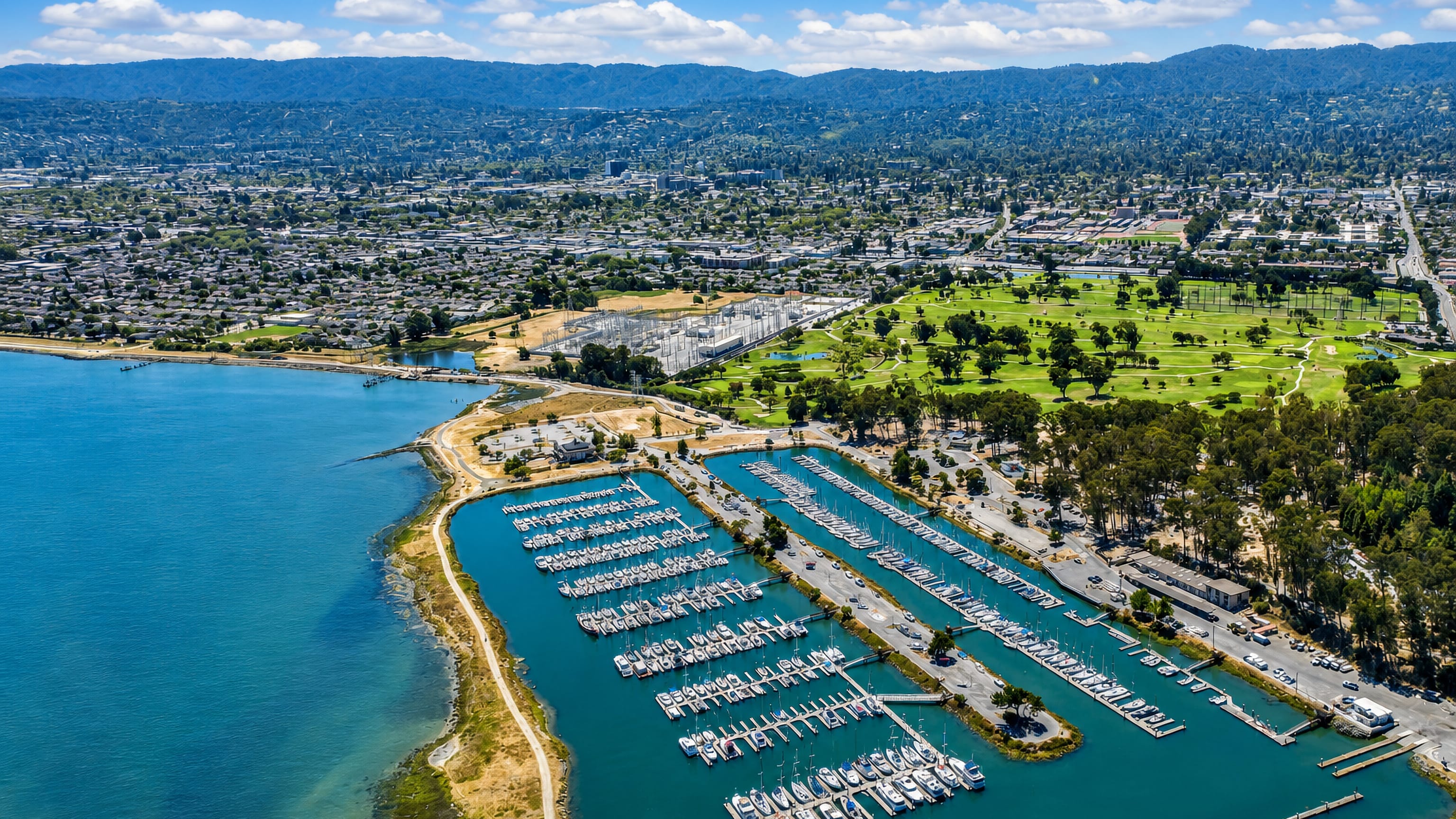 Sailboats packed into San Mateo's bayside marina in California, with the city and Peninsula hills behind.