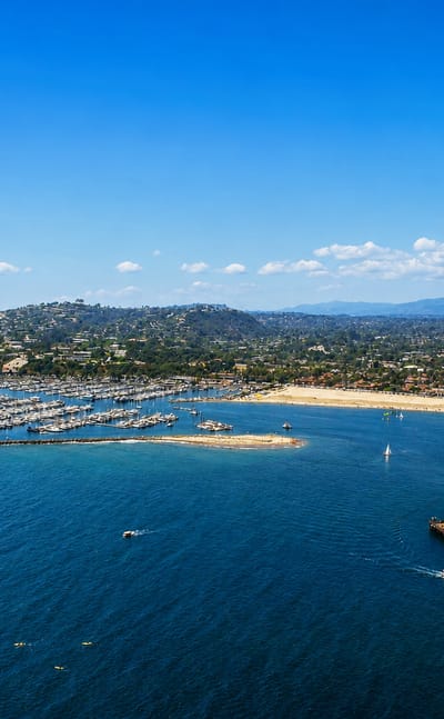 Aerial view of Santa Barbara's harbor, marina and Stearns Wharf with the coastline and mountains beyond