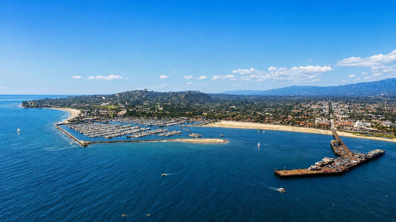 Aerial view of Santa Barbara's harbor, marina and Stearns Wharf with the coastline and mountains beyond