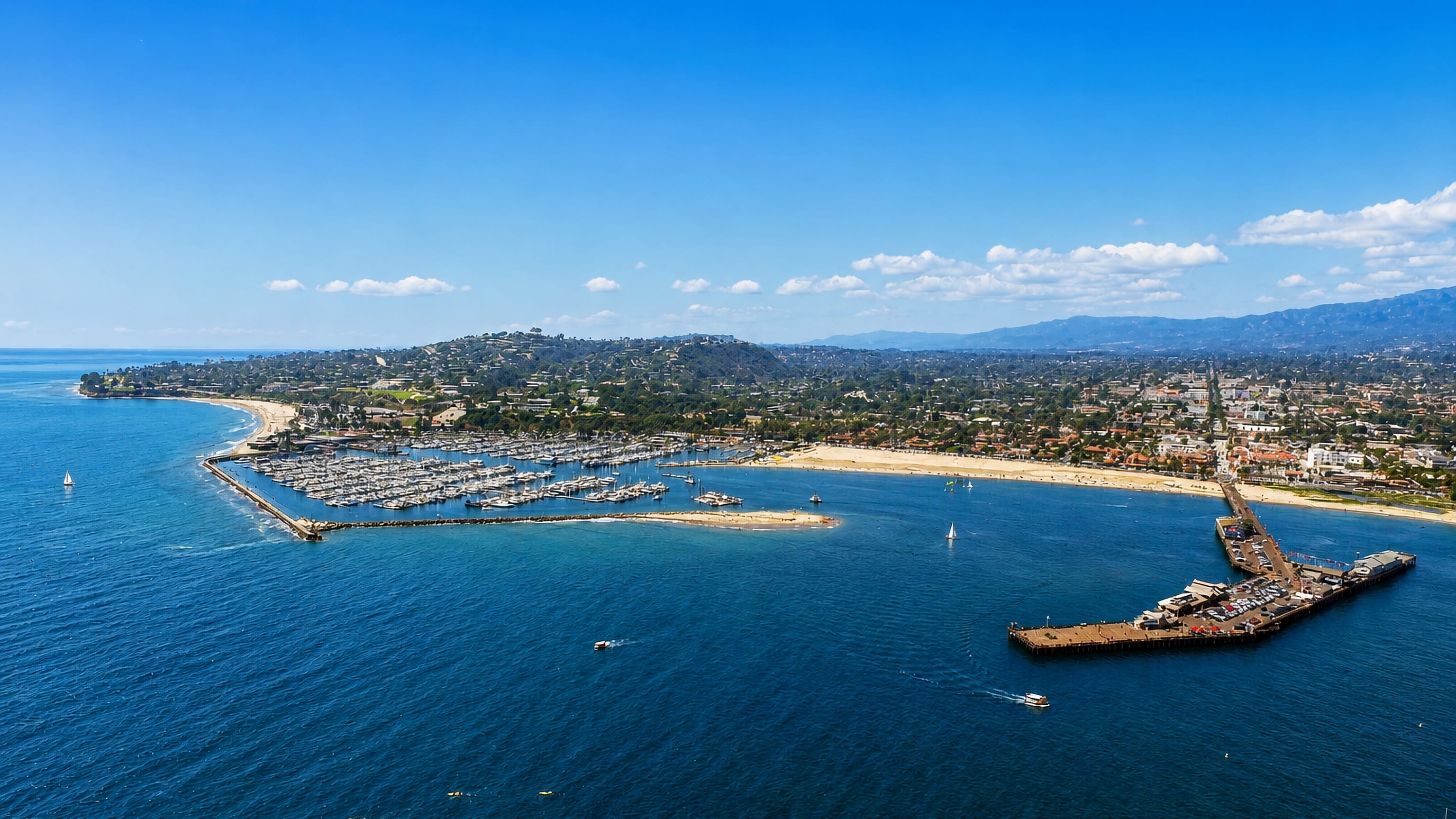 Aerial view of Santa Barbara's harbor, marina and Stearns Wharf with the coastline and mountains beyond