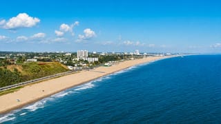 Aerial view of Santa Monica's sweeping sandy beach, coastal bluffs and low-rise skyline along the Pacific.