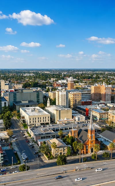Aerial view of downtown Stockton, California with mid-rise buildings, a twin-spired church and freeway