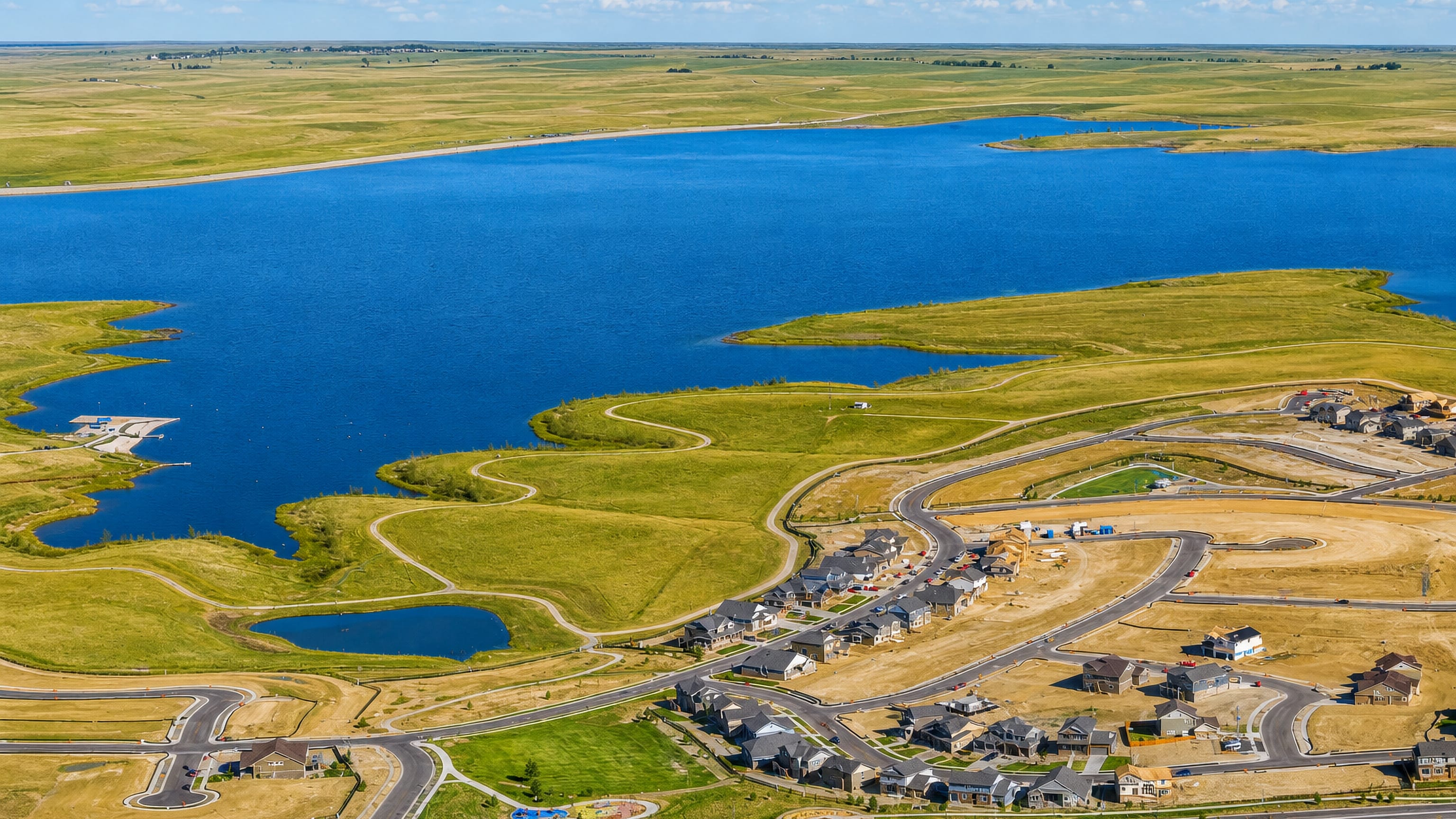 Aerial view of Aurora, Colorado, where new subdivisions meet a prairie reservoir under a clear blue sky.
